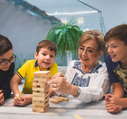 A joyful family moment with grandma and grandsons playing Jenga indoors, capturing quality time together.