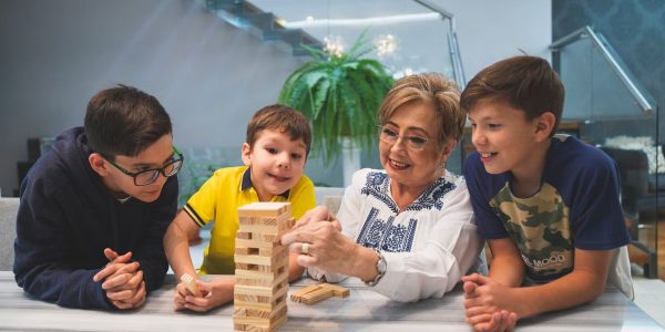 A joyful family moment with grandma and grandsons playing Jenga indoors, capturing quality time together.